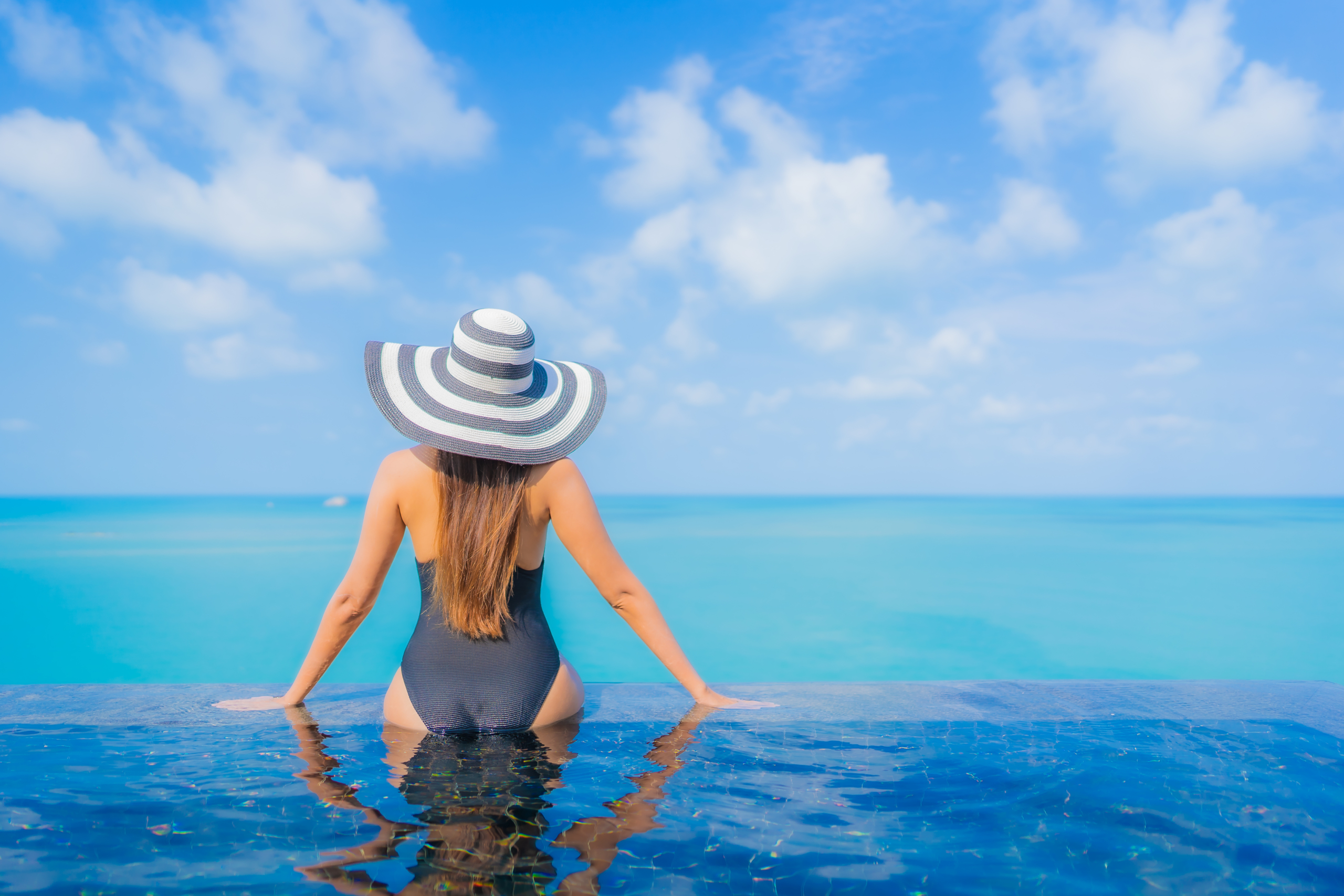 Portrait beautiful young asian woman relax smile leisure around outdoor swimming pool in resort hotel with sea ocean view